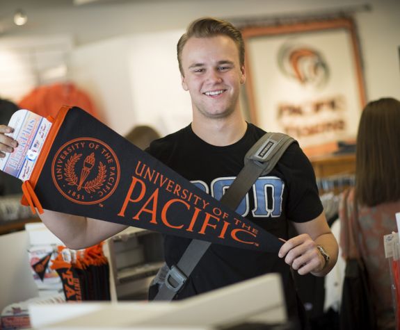 Smiling student holding Pacific pennant